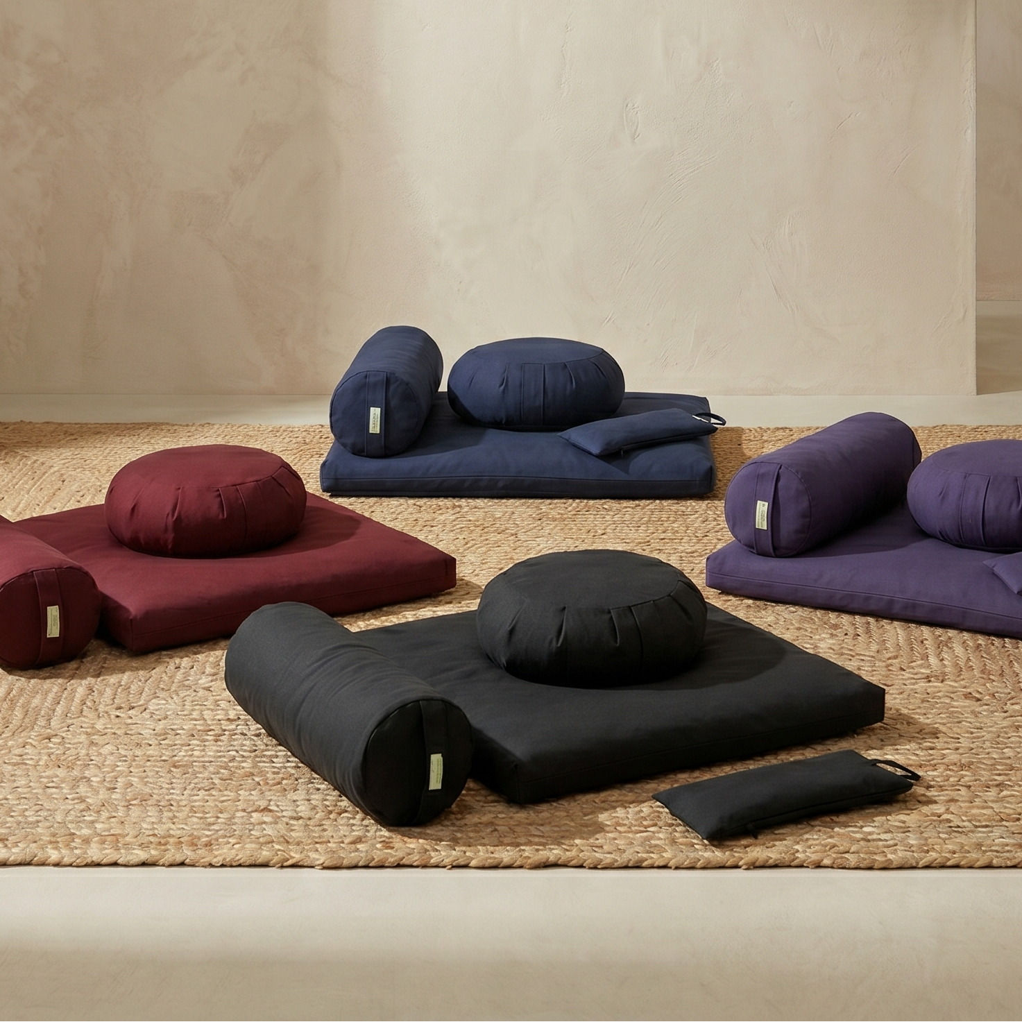 Set of meditation cushions and pillows on a woven mat with a neutral background