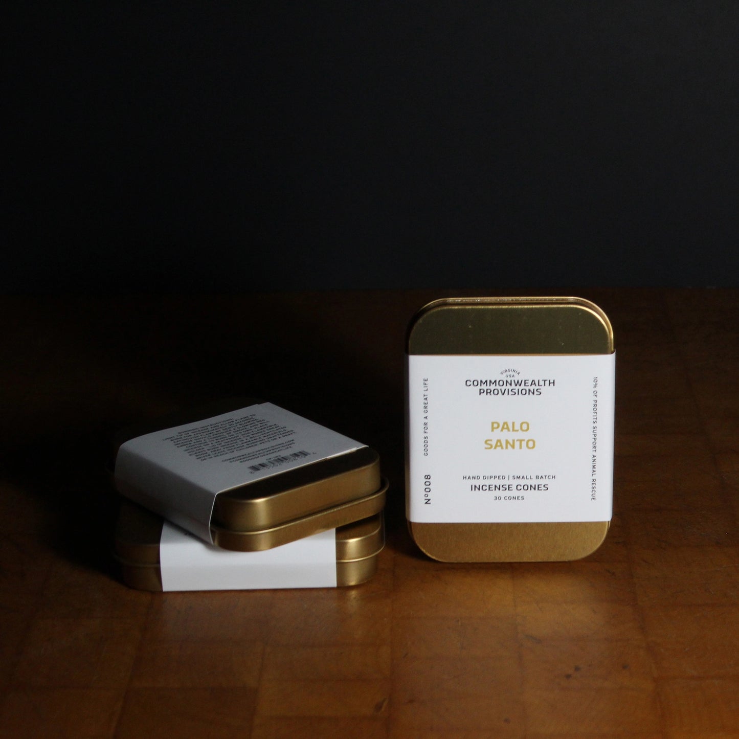 Two small metal tins with labels on a dark surface