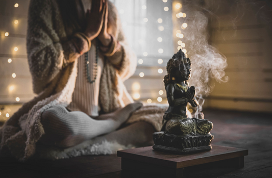 Buddha Statue with woman meditating in the back