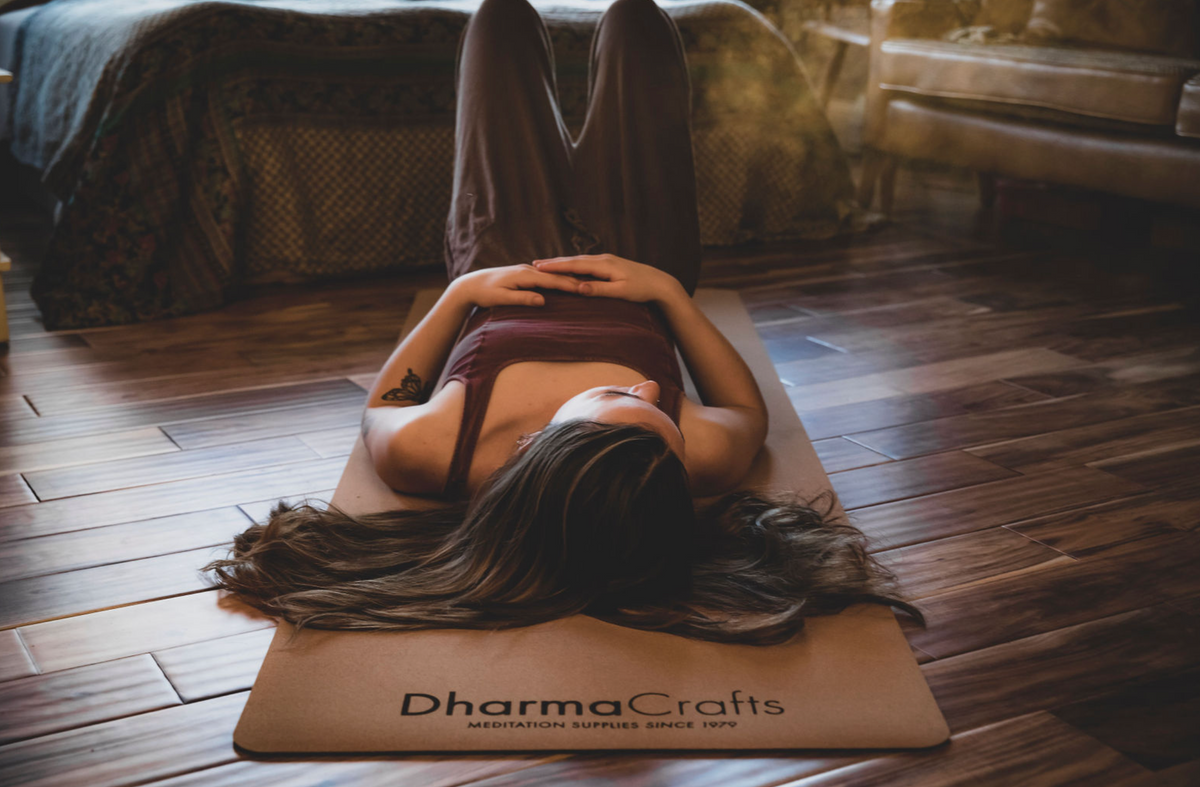woman laying on cork yoga mat in a wooden room
