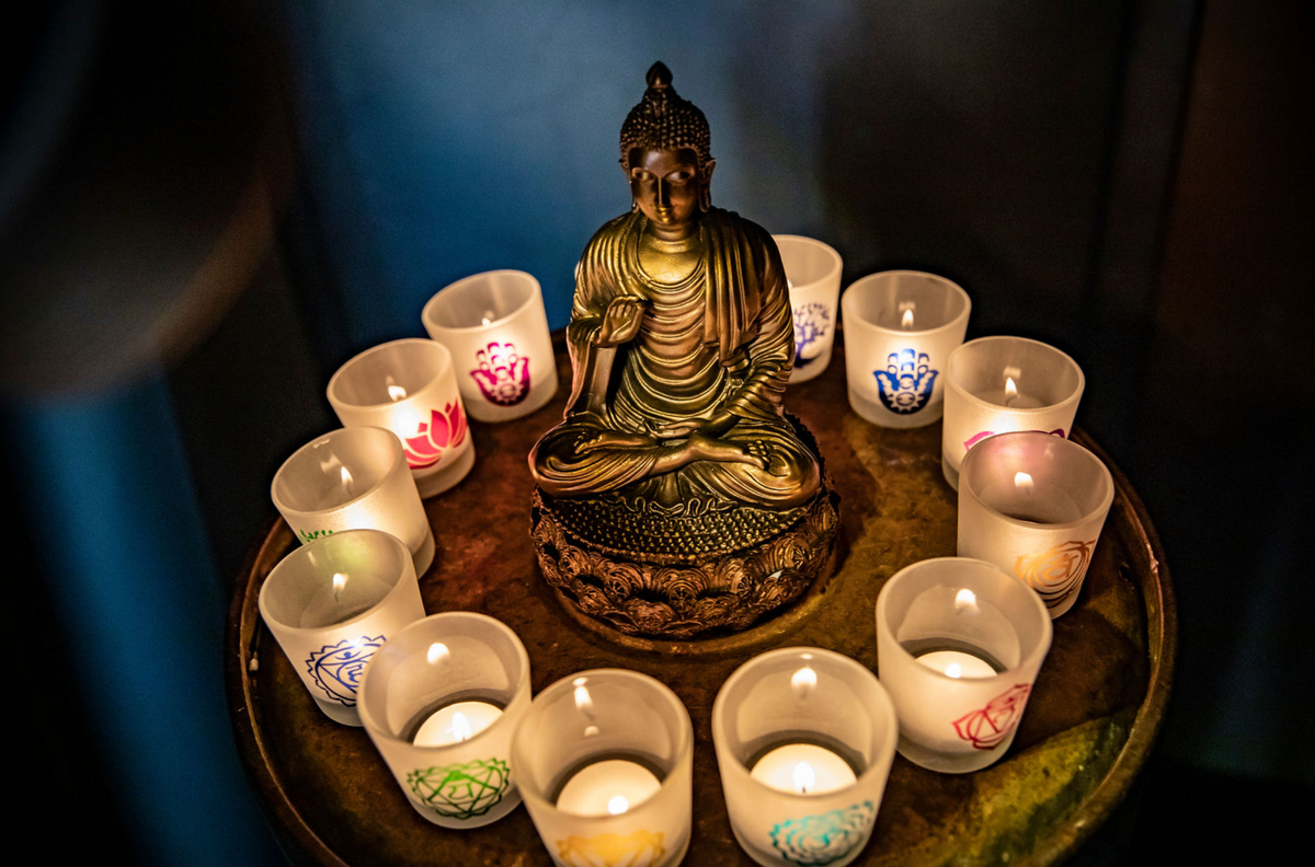 candles and a buddha sitting on a table 