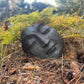 Black stone with facial design in a forest setting