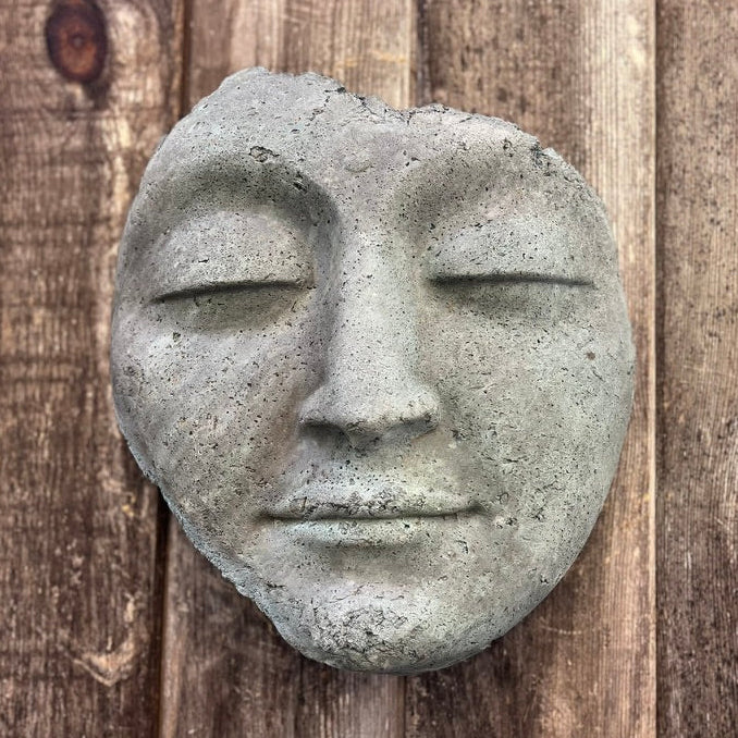 Concrete face sculpture on a wooden background