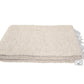 Beige woven blanket with tassels on a white background