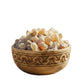 Wooden bowl filled with white stones in a room with plants and a Buddha statue.