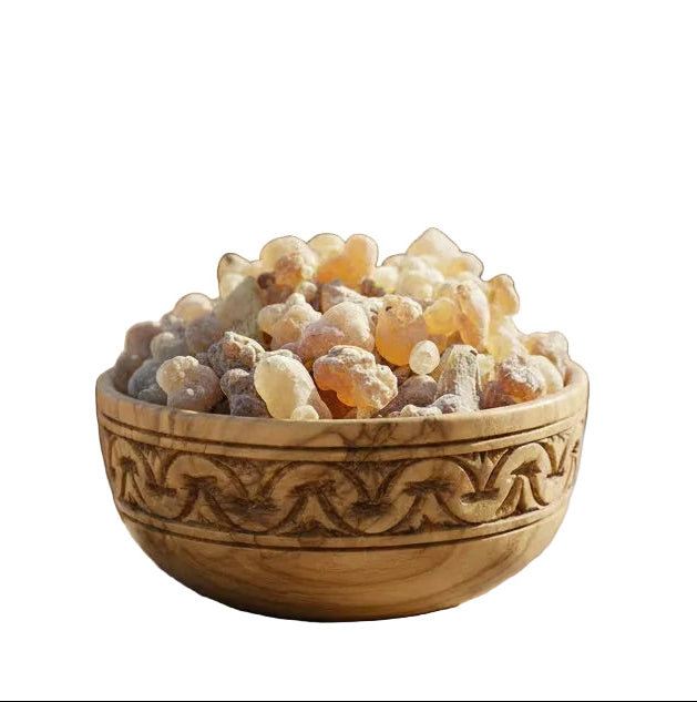 Wooden bowl filled with white stones in a room with plants and a Buddha statue.