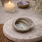 Abalone shell on a stone surface with a candle and amethyst stones in the background