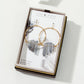 Gold hoop earrings with gray stones on a branded card in a box