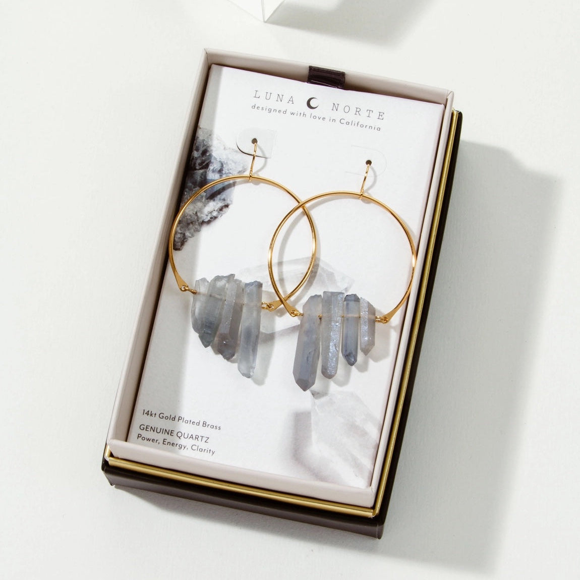 Gold hoop earrings with gray stones on a branded card in a box