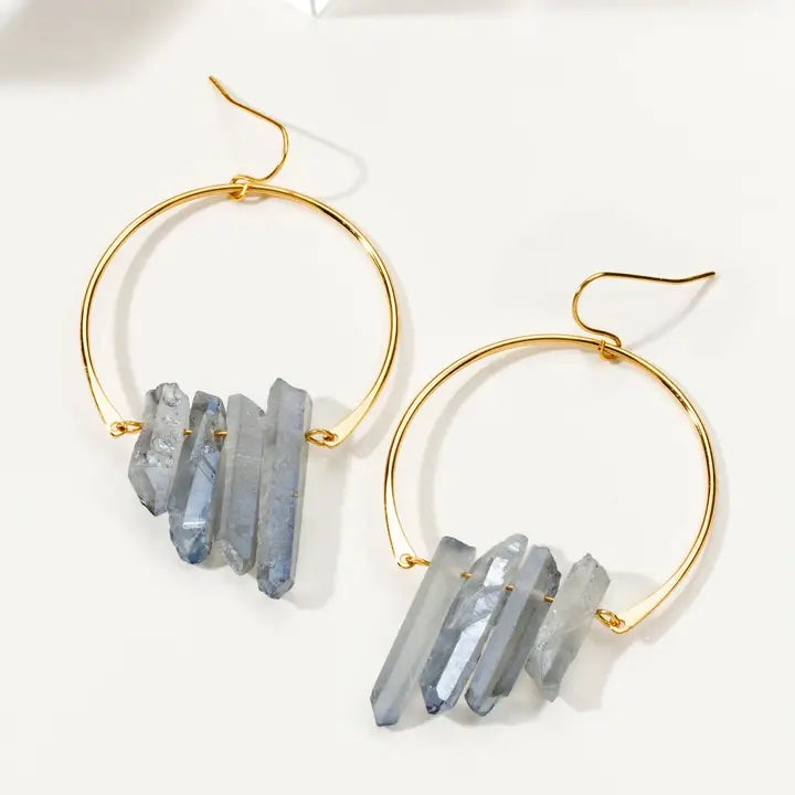 A pair of gold hoop earrings with clusters of natural gray-blue crystal points hanging from the hoops, displayed on a clean white background.