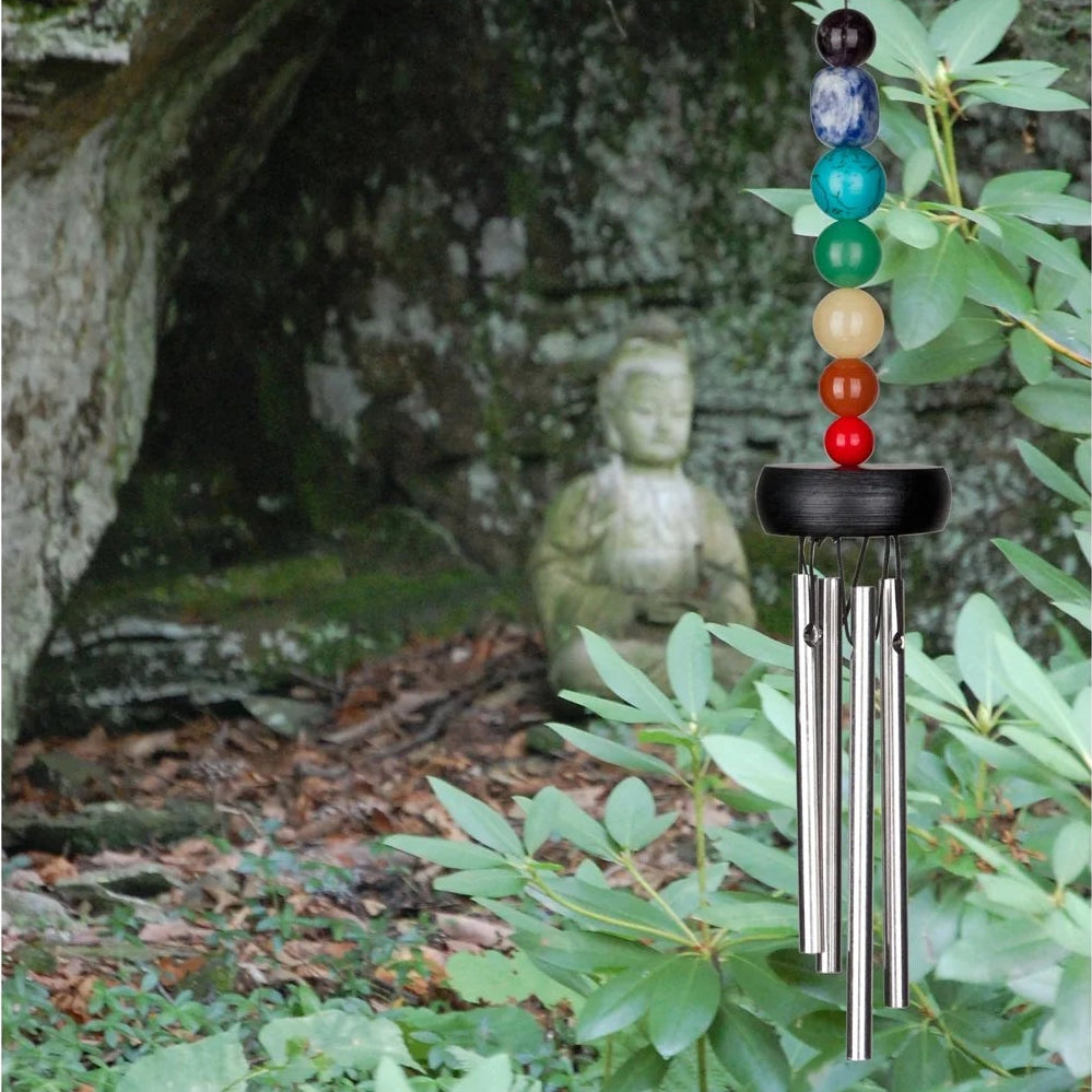 Chakra wind chime with a stone statue in a forest setting