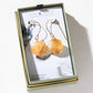 Luna Norte 14k gold-plated brass geometric citrine dangle earrings displayed inside their light sage green and gold presentation box.