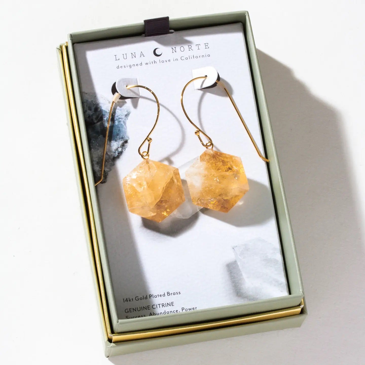 Luna Norte 14k gold-plated brass geometric citrine dangle earrings displayed inside their light sage green and gold presentation box.