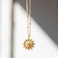 Gold necklace with pendant on a white wall.