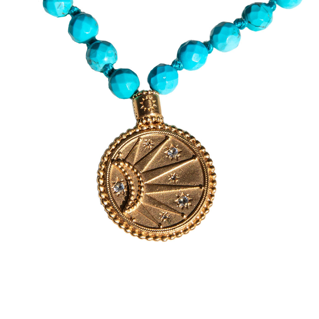 Turquoise beads and gold pendant mala on a white background.
