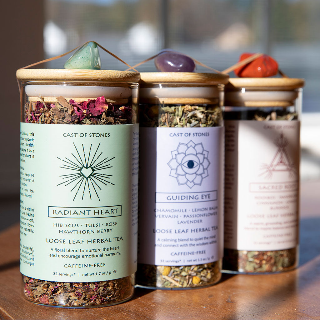 Three glass jars with herbal tea blends on a wooden surface