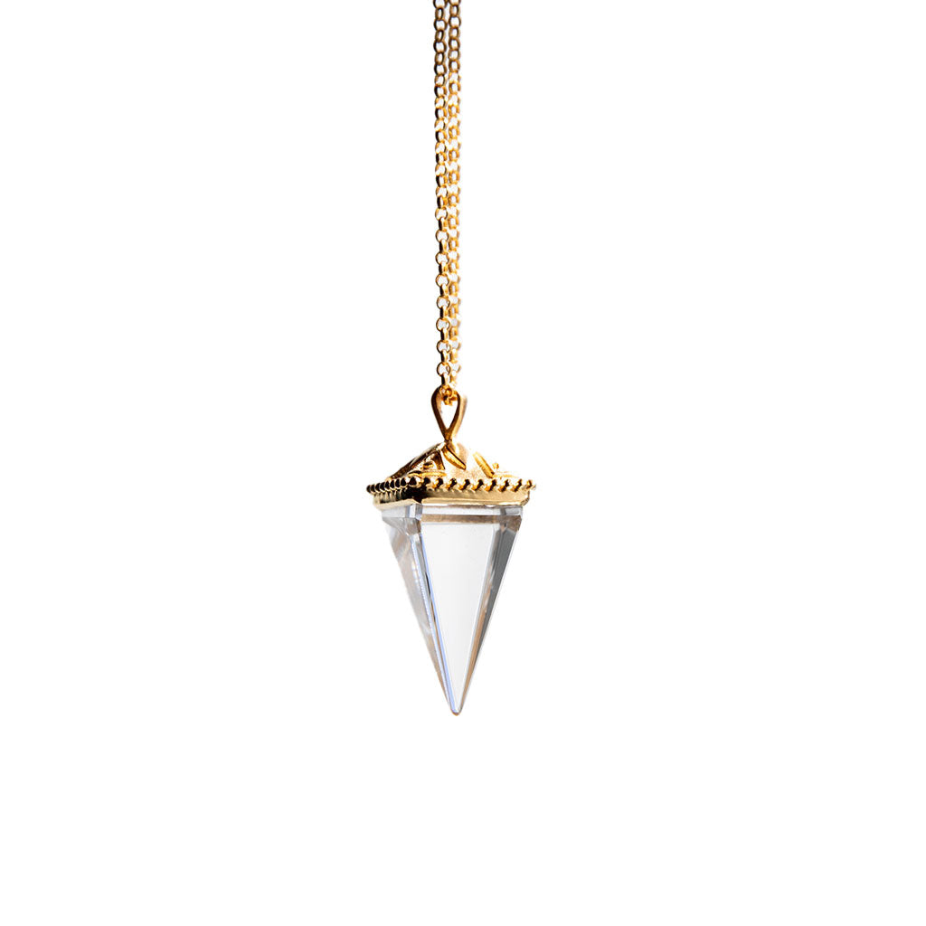 Crystal pendant on a gold necklace up against a white background.