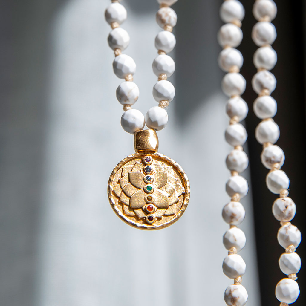 White turquoise mala with gold pendant hanging.