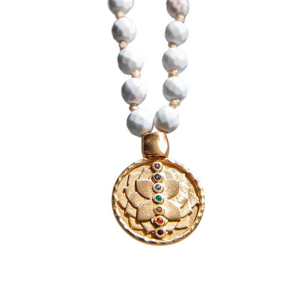 White turquoise mala with gold pendant on white background.