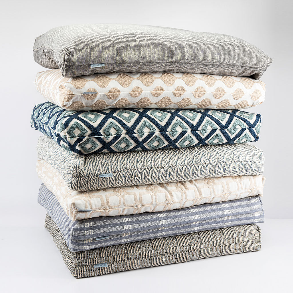 Stack of folded fabric swatches in various patterns and colors on a white background