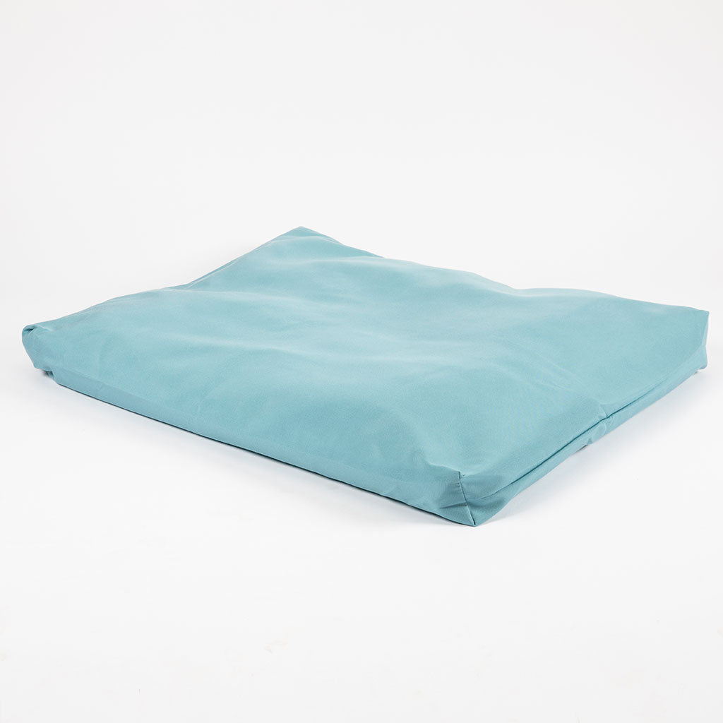 A light blue rectangular fabric cushion or floor pad with a soft, slightly wrinkled surface, photographed on a seamless white background.