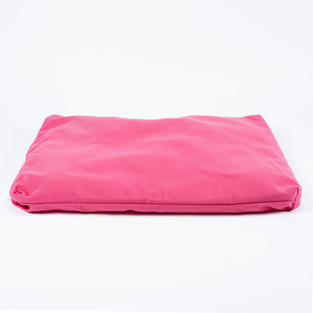 A bright pink rectangular cushion or pillow, folded slightly at the edges, photographed on a seamless white background.