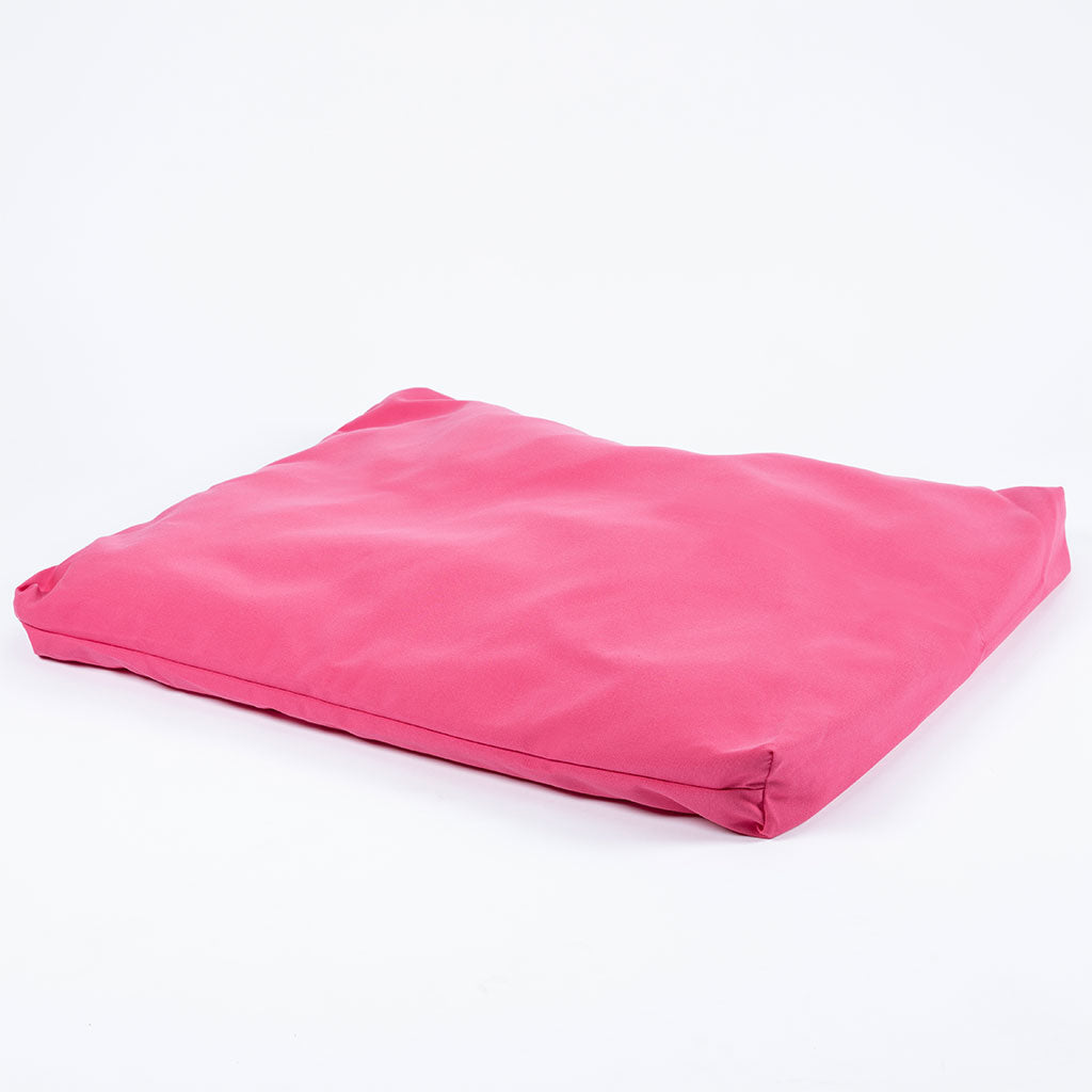 A bright pink rectangular floor cushion or meditation pad with a smooth fabric surface, photographed on a seamless white background.