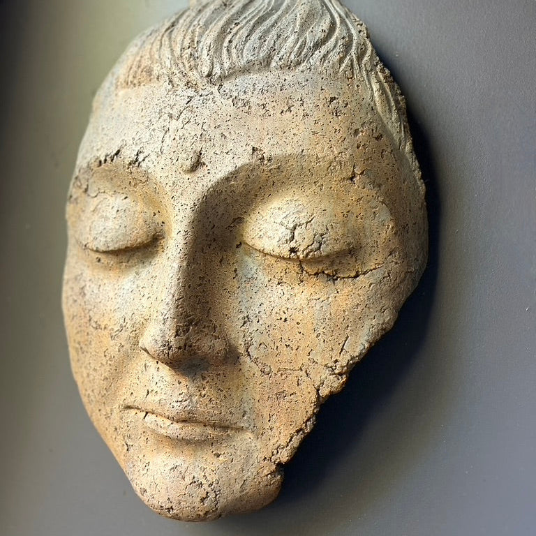 Stone sculpture of a face on a gray background