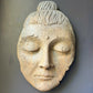 Stone sculpture of a face with closed eyes on a gray background