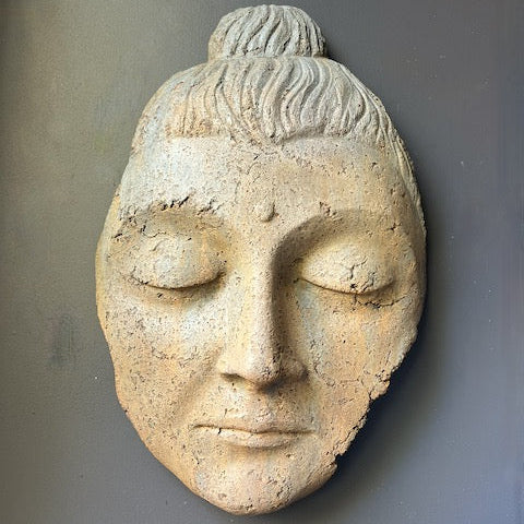 Stone sculpture of a face with closed eyes on a gray background
