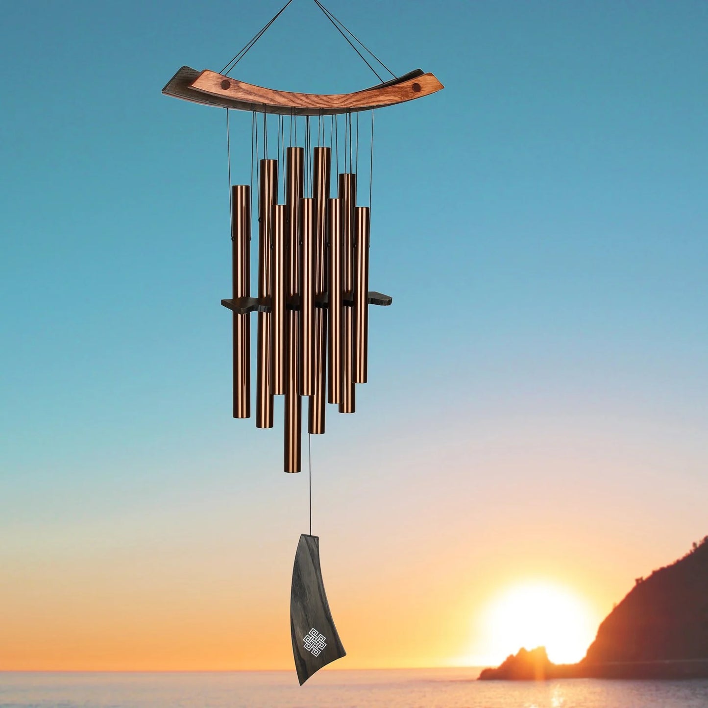 Wind chime hanging against a sunset sky with mountains in the background