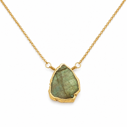 A gold chain necklace featuring a raw, irregular-shaped green labradorite stone pendant with a textured gold border, shown on a clean white background.