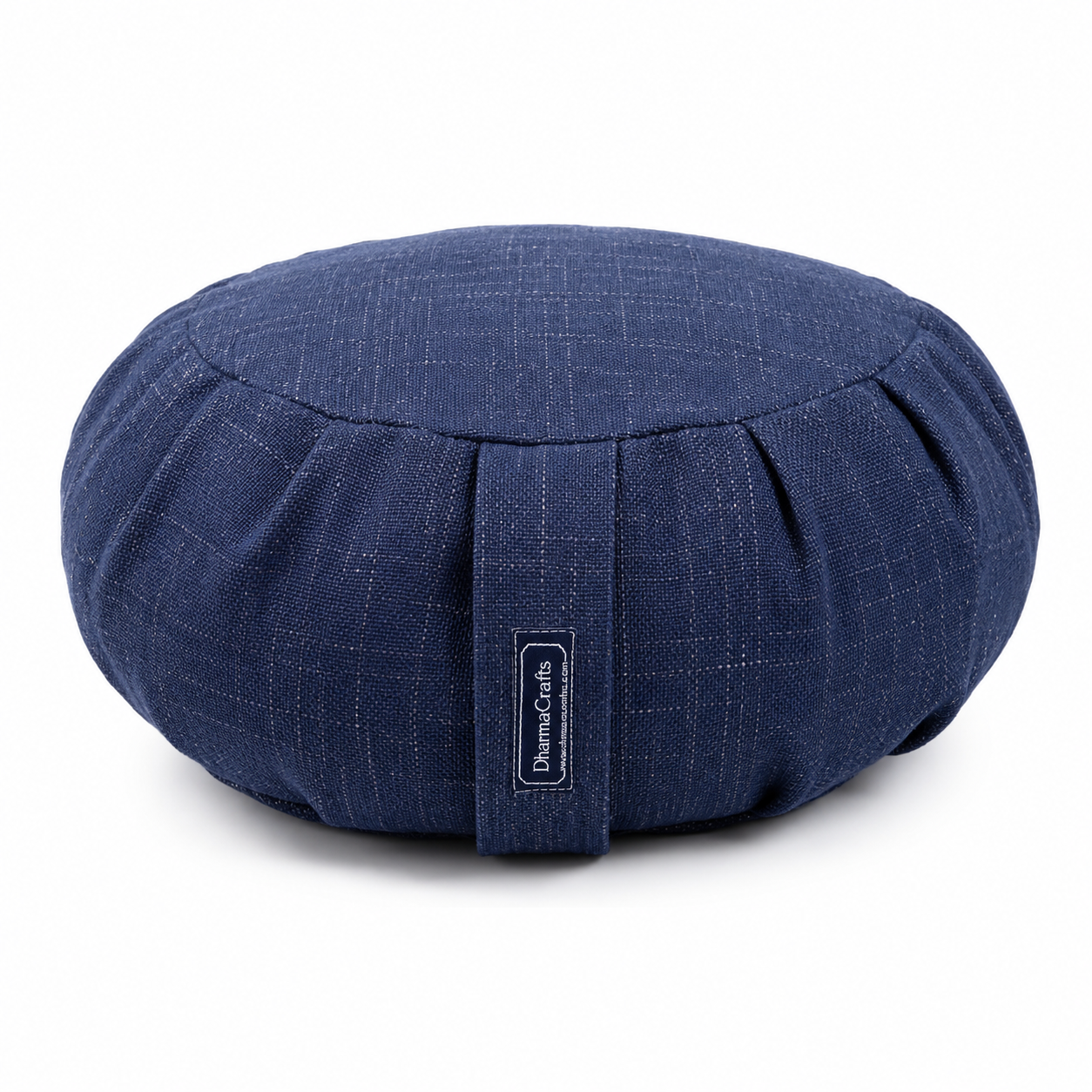 A round navy blue fabric cushion with a subtle woven texture and a central strap featuring a vertical label that reads 'DharmaCraft'. The cushion is photographed on a clean white background with a soft shadow underneath.