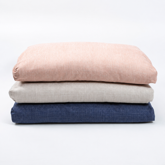 Three folded textured fabric cushions stacked vertically on a clean white background, in dusty pink, light beige, and navy blue.