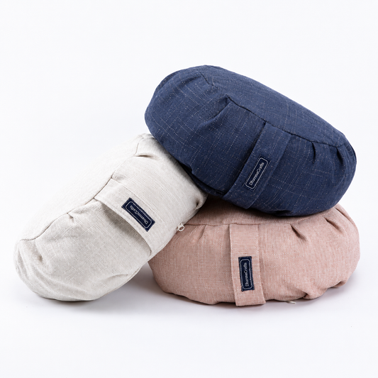 Three round fabric meditation or floor cushions stacked together on a white background. The top cushion is navy blue, the middle cushion is off-white/cream, and the bottom cushion is dusty pink.
