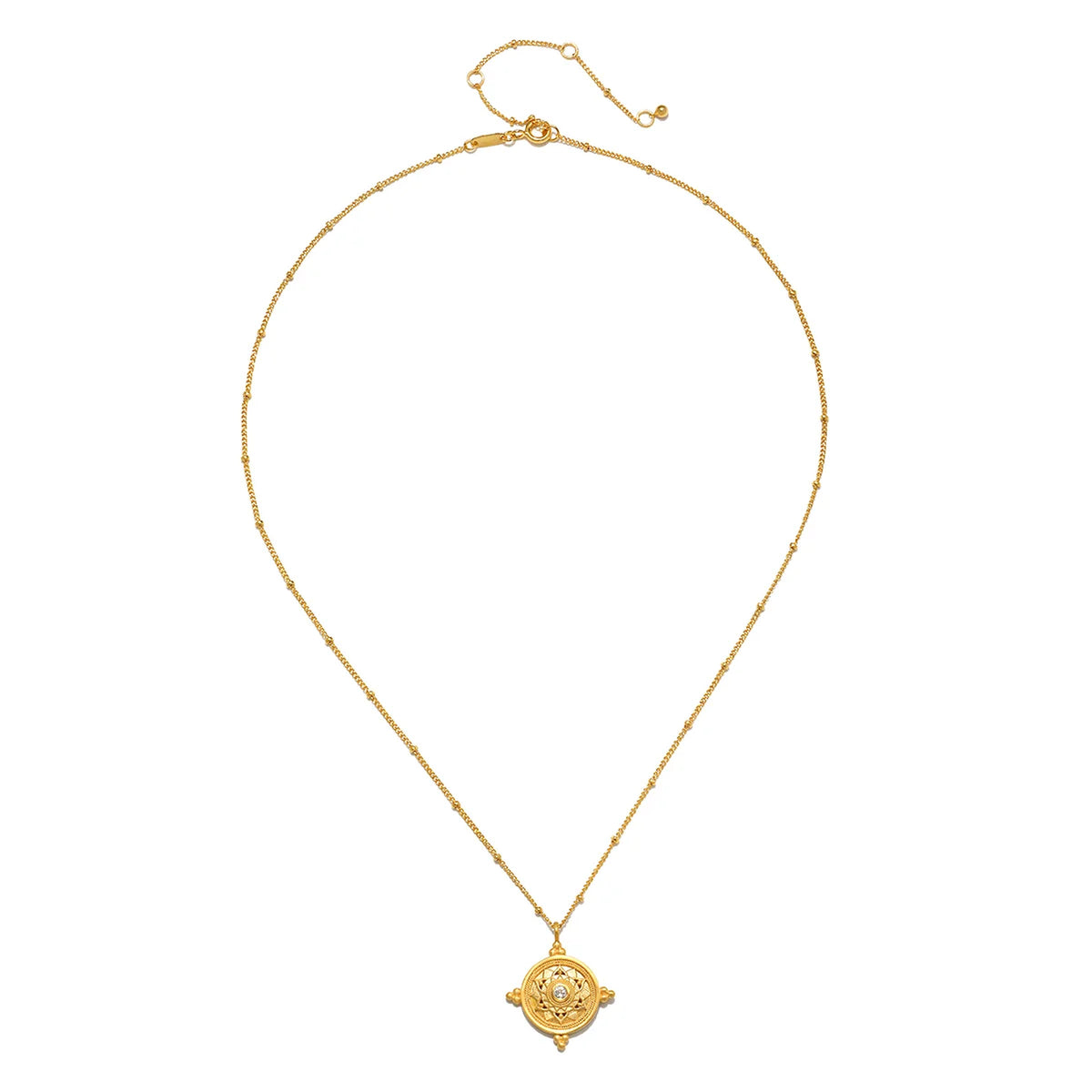 A delicate gold chain necklace with a small circular pendant featuring a central clear stone and surrounding gold detailing, displayed on a clean white background.