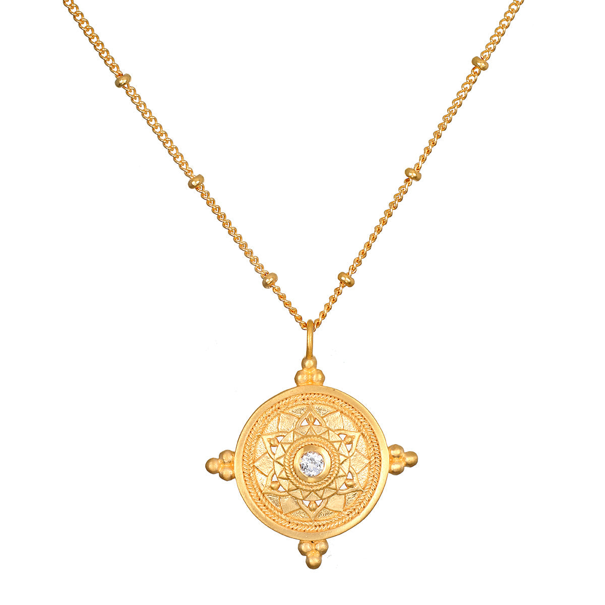 A gold pendant necklace featuring an ornate circular medallion pendant with a central clear gemstone, displayed on a clean white background.