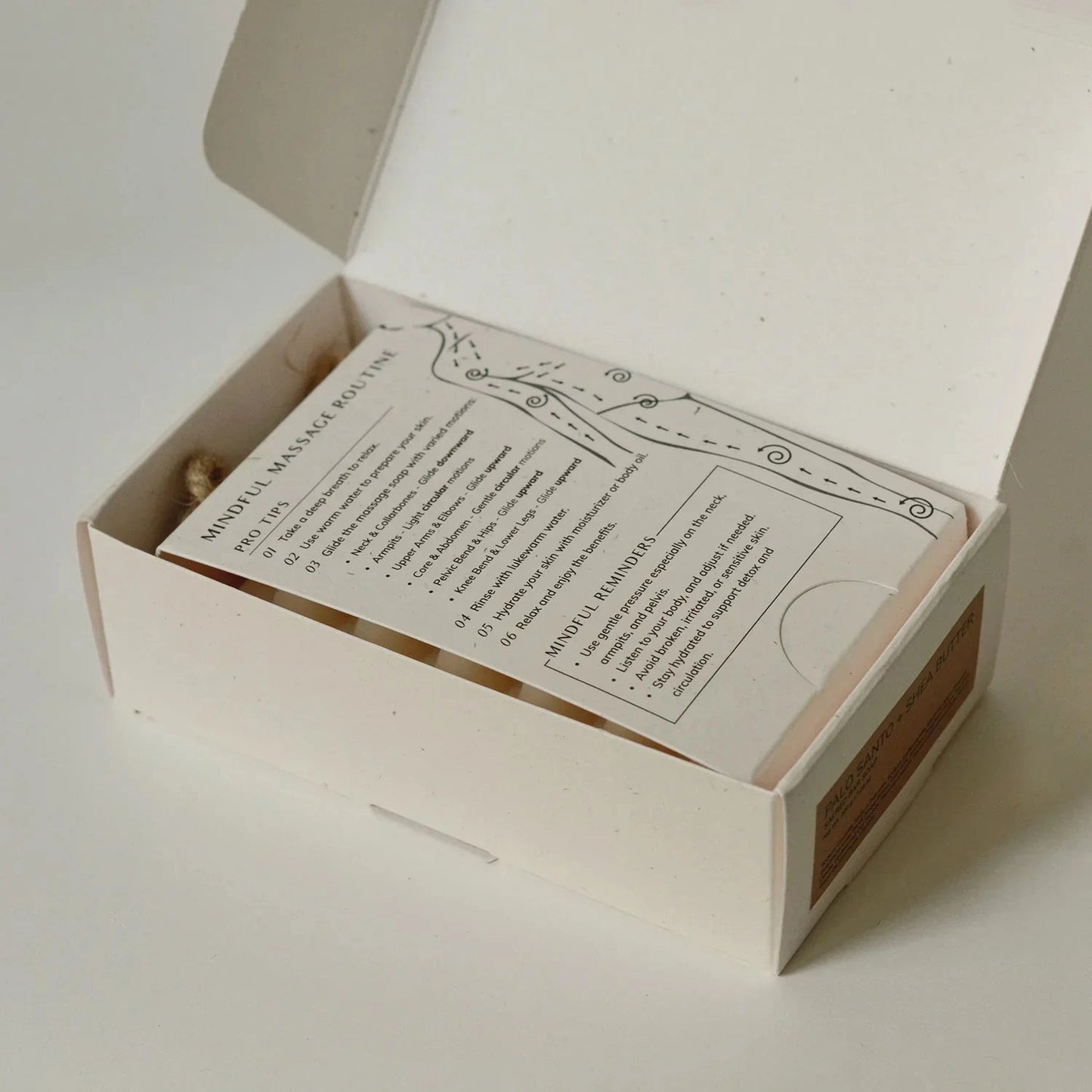 Box with a sheet for mindful massage routine directions on a white background.