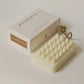 Massage soap bar laying on a white surface with a box next to it.