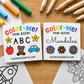 Two small coloring mini books laid on a wooden surface, surrounded by colored pencils and crayons. The left book is titled "Color-Me! Mini Book ABC" with illustrations of a star, letter A, apple, teddy bear, and car.