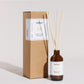 Reed diffuser with bottle and cardboard box on a light gray background