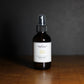 Room spray bottle labeled 'Palo Santo' on a wooden surface with a dark background