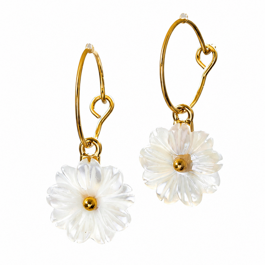 A pair of gold hoop earrings with dangling white daisy flower charms, shown against a plain white background.