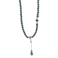 Mala necklace with black beads and colorful pendant on a light gray background