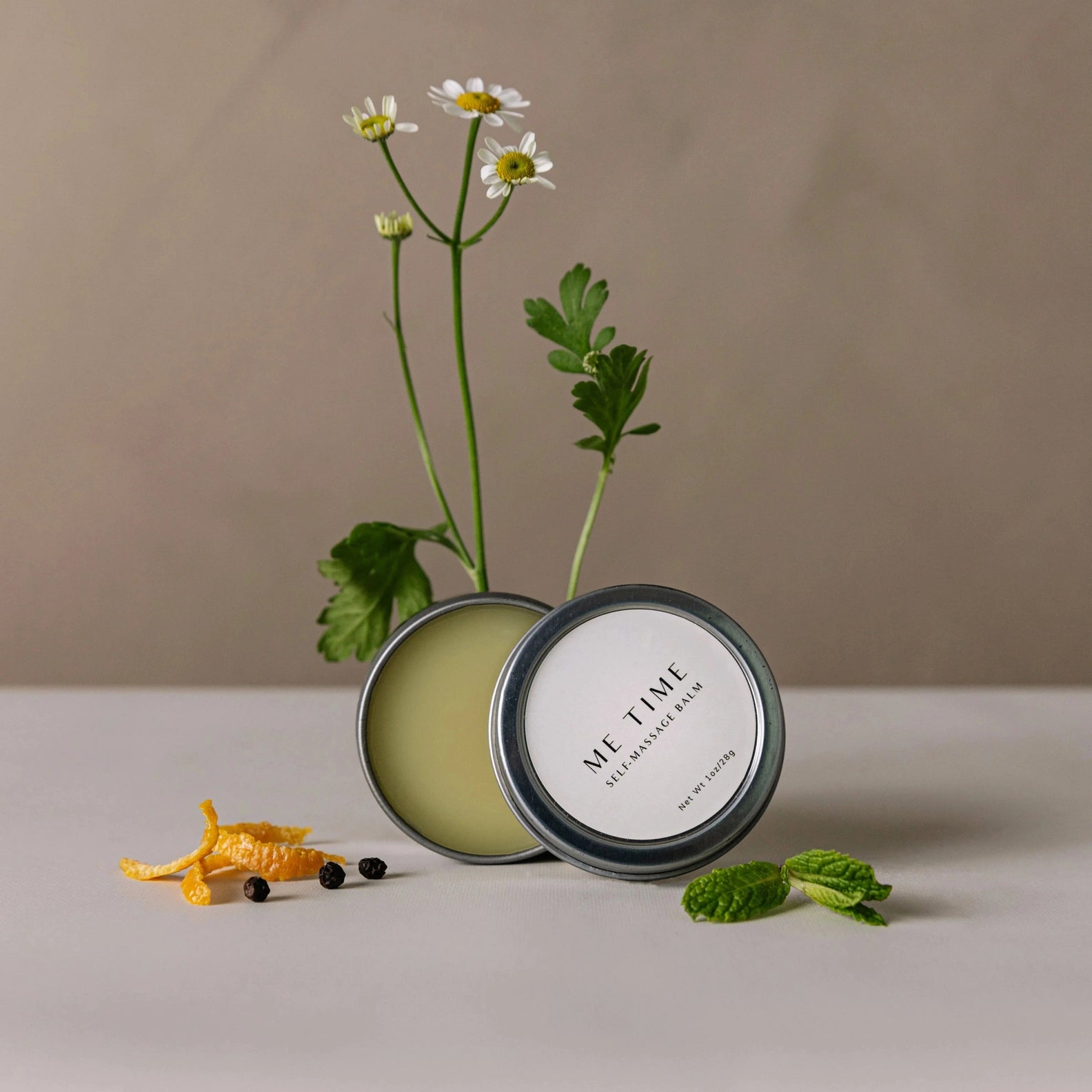 Candle with 'Me Time' label and flowers on a neutral background