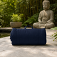 Navy blue roll-up mat on a stone surface with a Buddha statue and greenery in the background