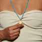 Turquoise beads and gold pendant mala on a woman.