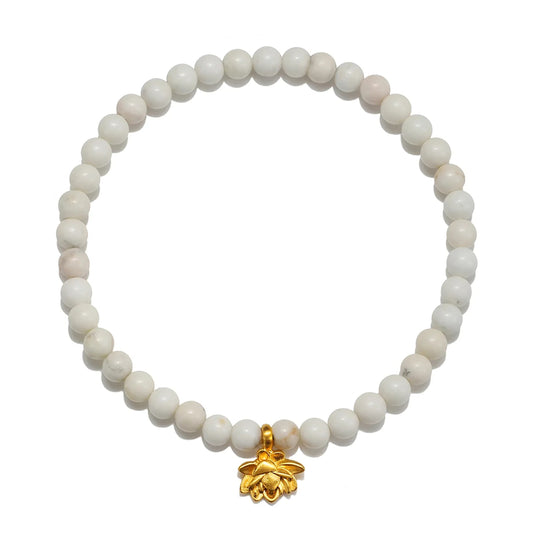 A beaded stretch bracelet made of round off-white stone beads with a small gold bee charm at the bottom center, shown on a plain white background.