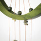 Decorative hanging with green stones and copper strings on a white background