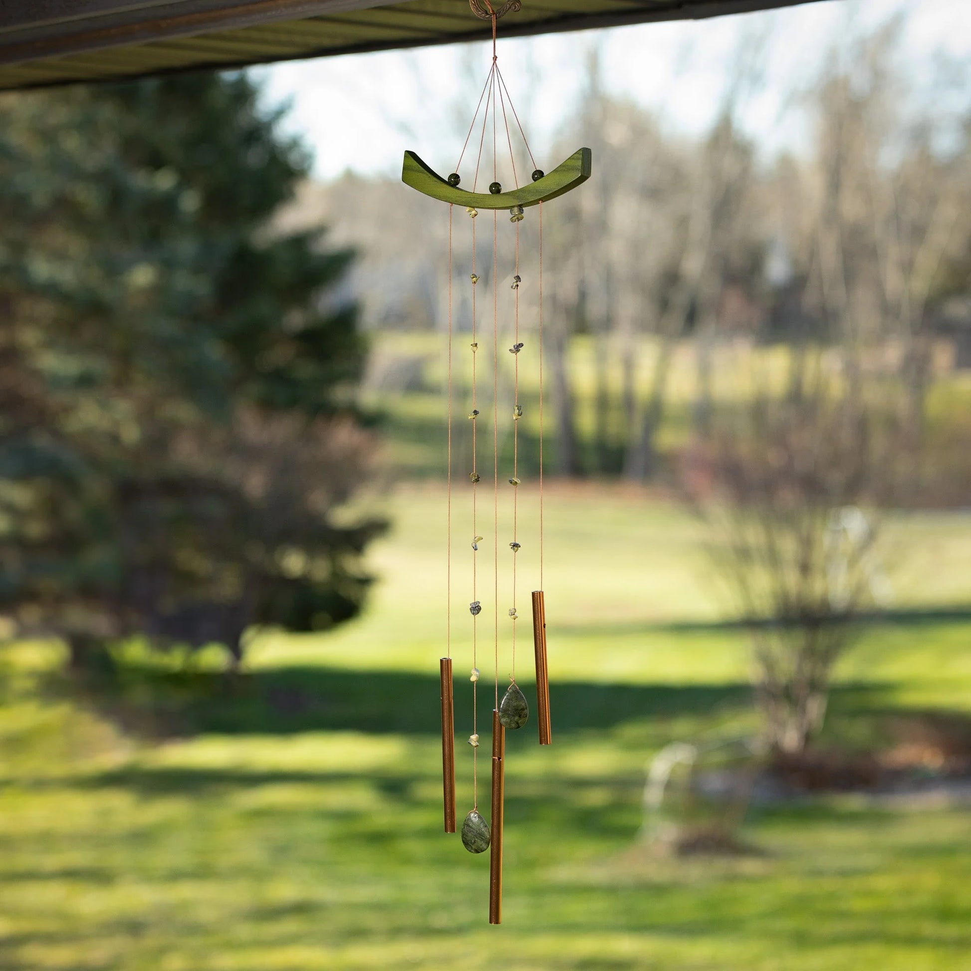 Decorative wind chime hanging outdoors with a garden background